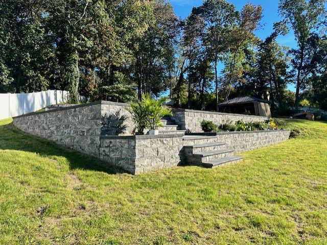 A stone wall with stairs leading up to it is in the middle of a lush green field.