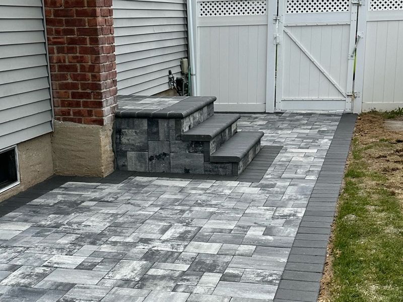 A beautifully designed paver walkway curving through a lush green garden.