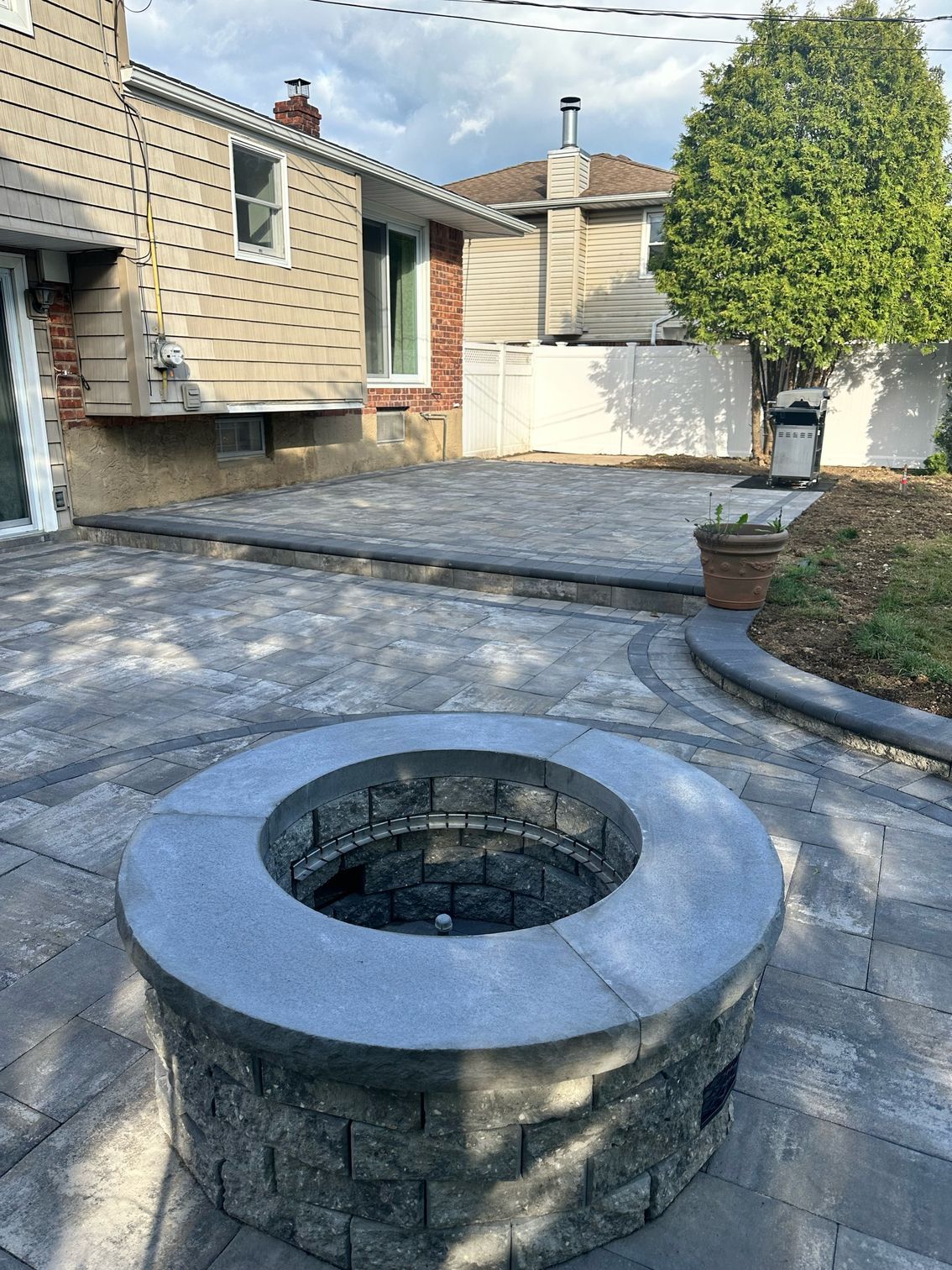 A fire pit is sitting on a patio in front of a house.