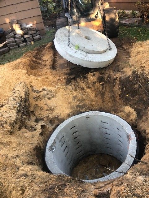 A concrete ring is being installed in a hole in the ground.
