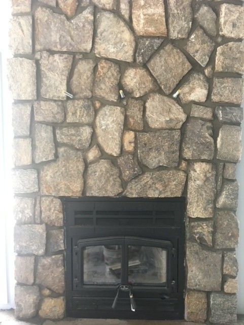 A stone fireplace with a black fireplace insert