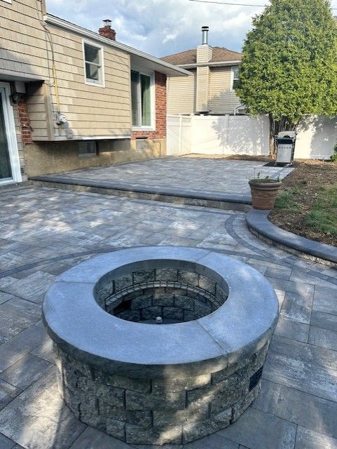 A fire pit is sitting on a patio in front of a house.