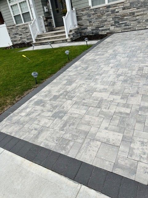 A driveway with a black border is in front of a house.