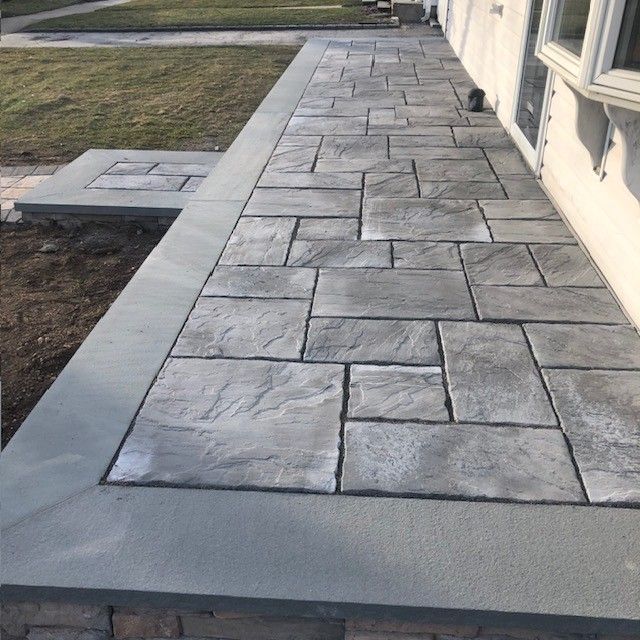 A stone walkway is being built in front of a house