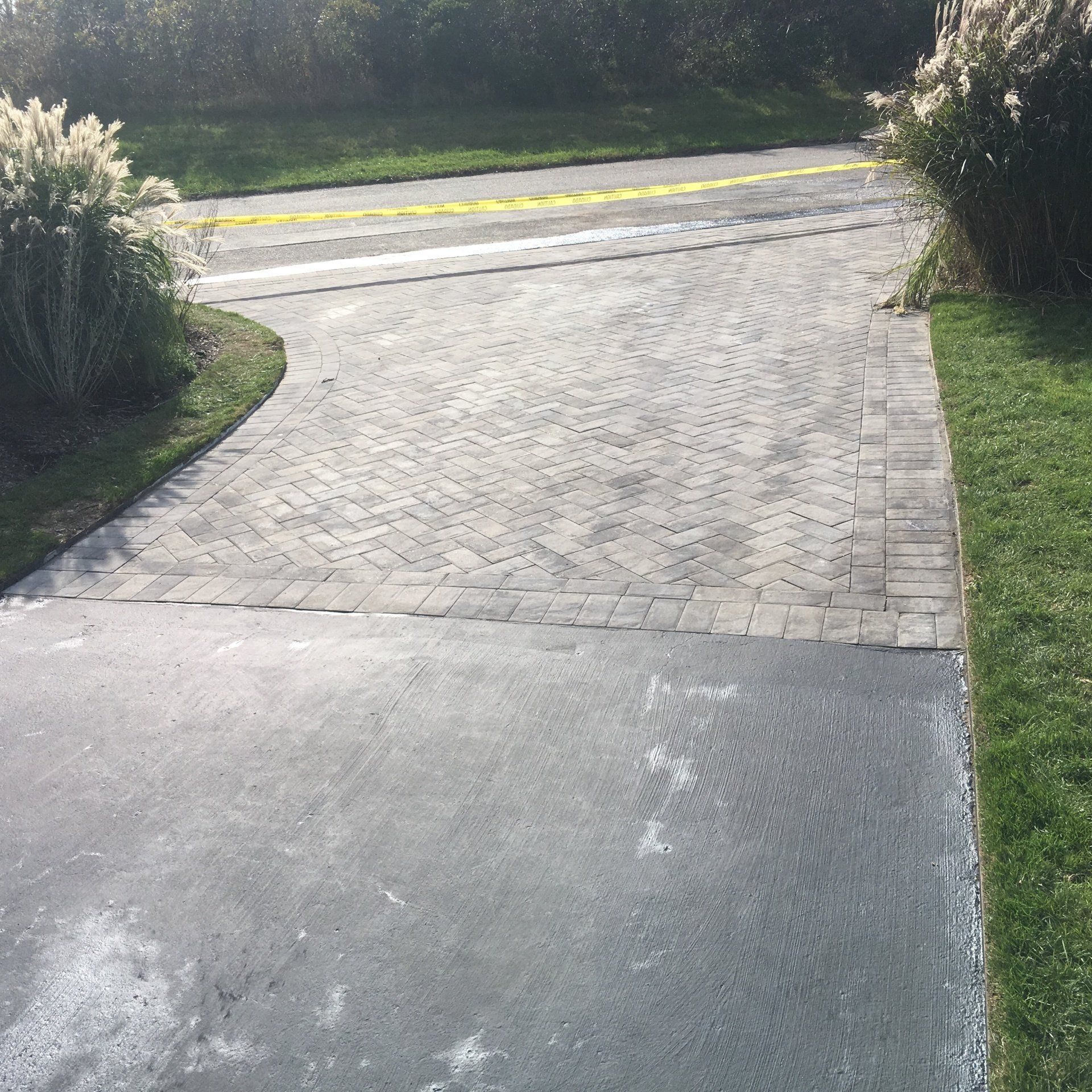 a driveway with grass and bushes