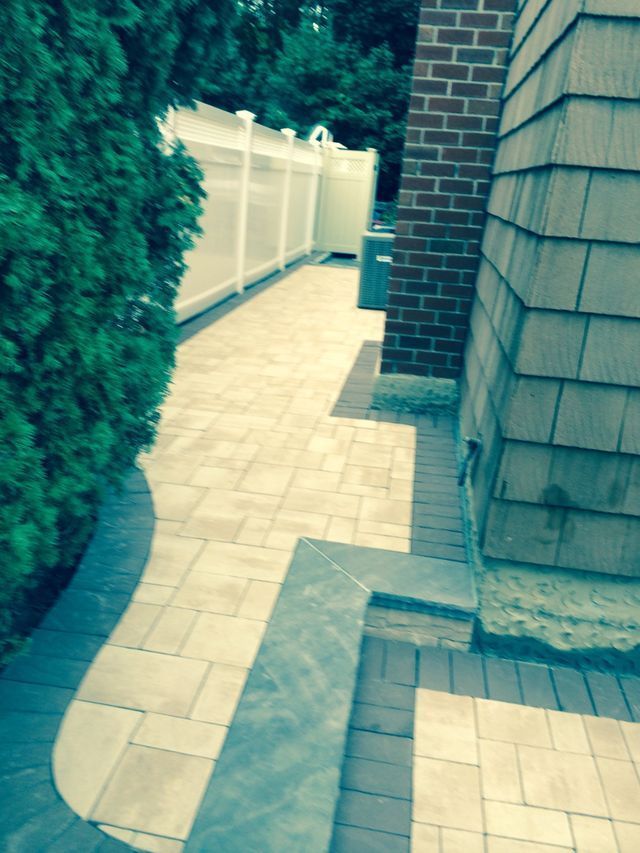 a brick walkway with a white fence and a brick wall