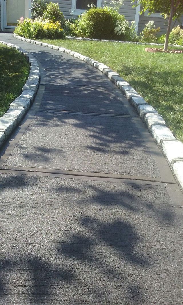 a paved path with grass and trees