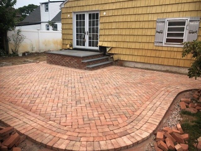 A yellow house with a brick patio in front of it