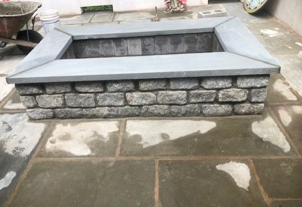 A brick fire pit is sitting on top of a brick patio.