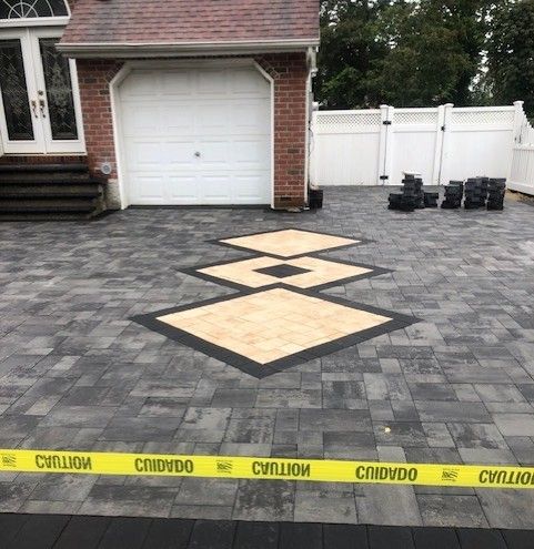 A brick driveway with a yellow caution tape around it in front of a house.