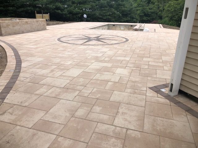 A patio with a compass on it and a pool in the background