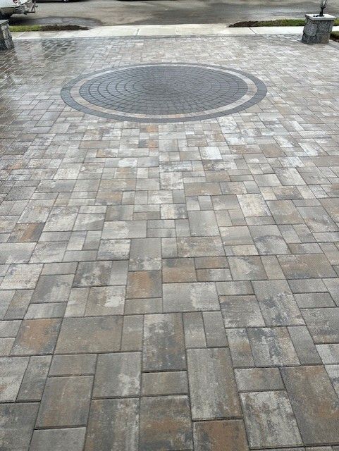 A brick driveway with a circular design in the middle.