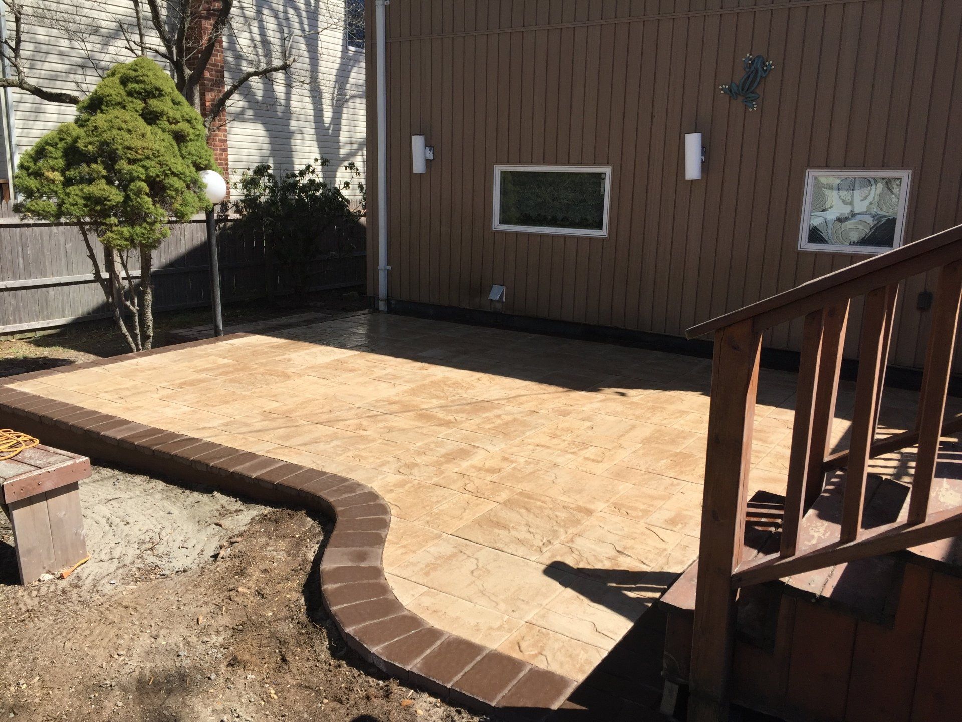 a patio with a wood staircase and a house