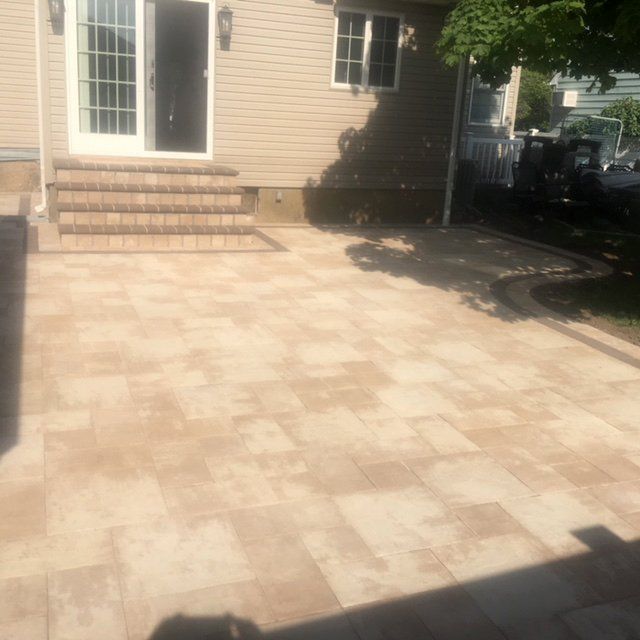 A patio with brick pavers and step with tree