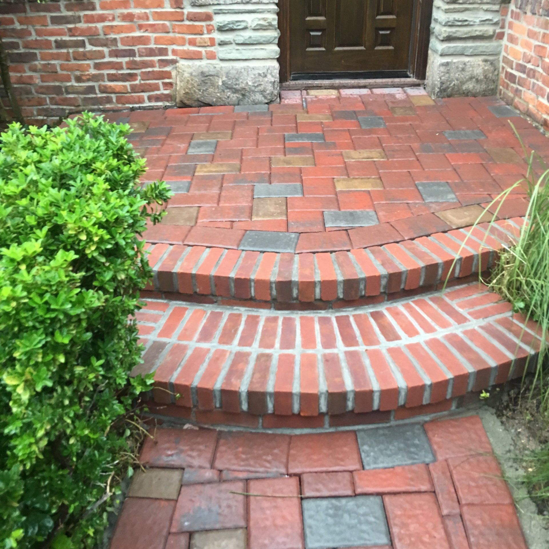 a brick walkway with steps and bushes