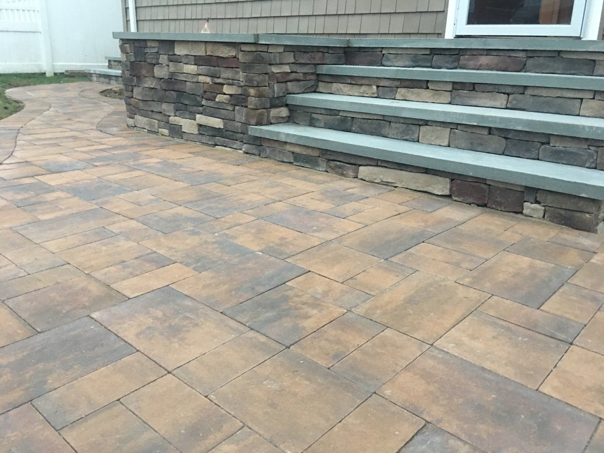 a stone patio with steps and a house