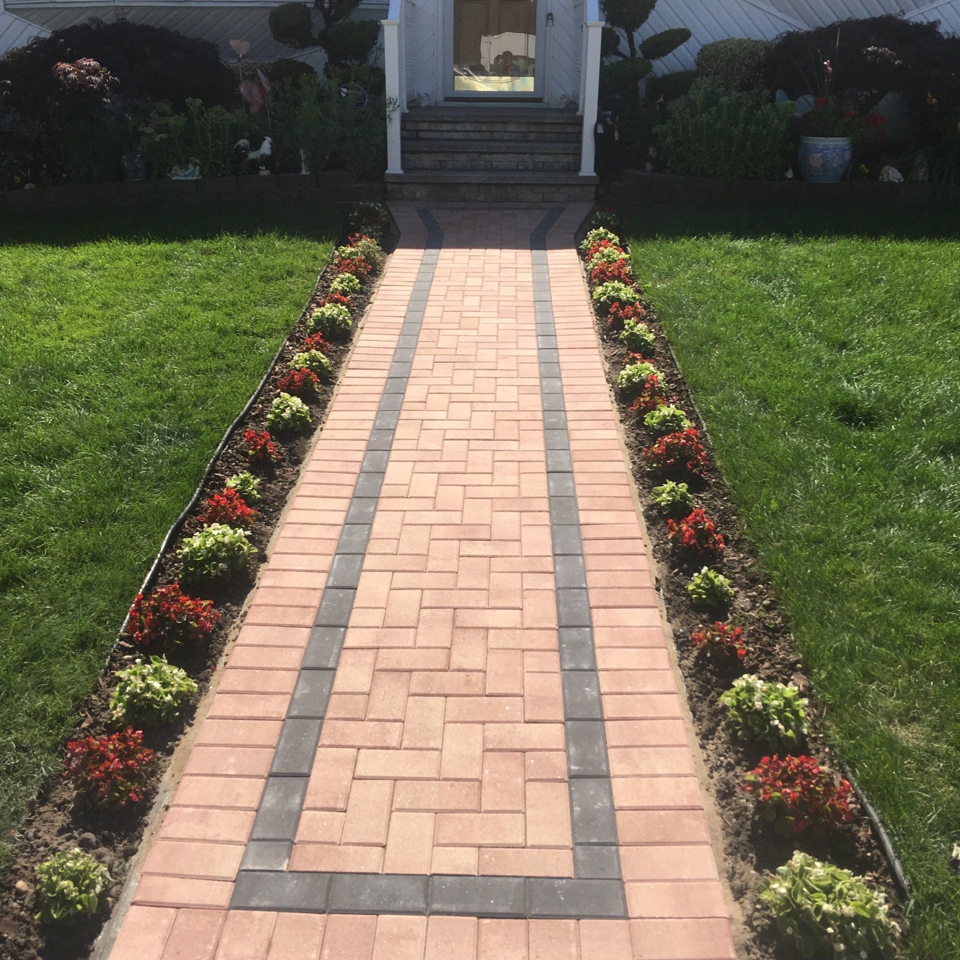 a brick walkway with flowers in front of a house
