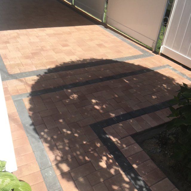 a brick patio with a fence and a tree shadow