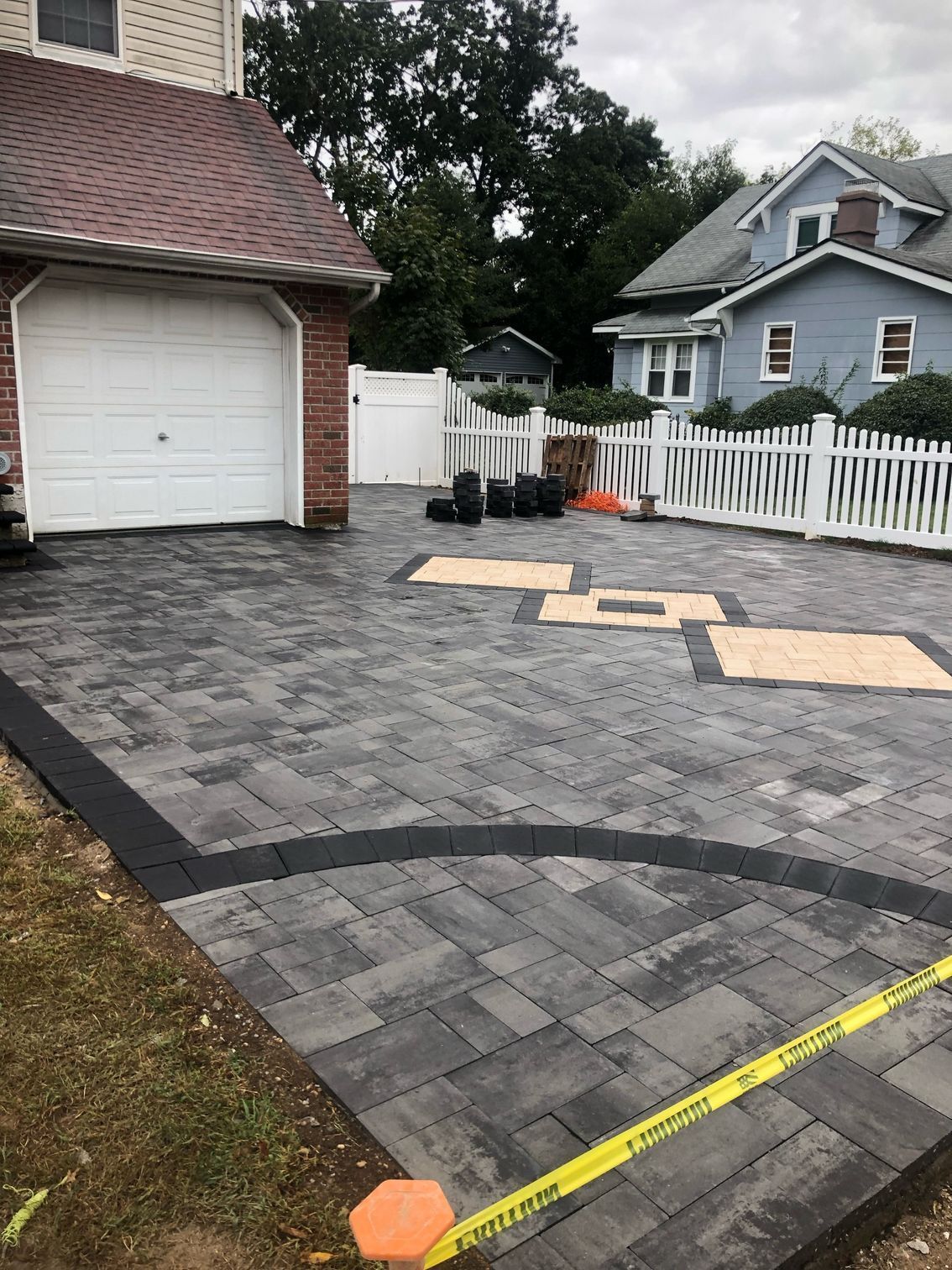 a driveway with a garage and a white fence