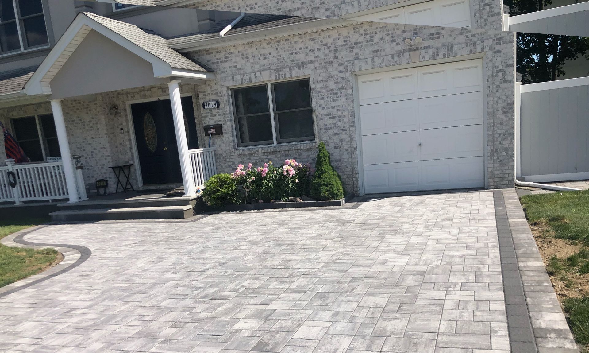 A beautifully designed paver walkway surrounded by greenery, leading to a modern home entrance.