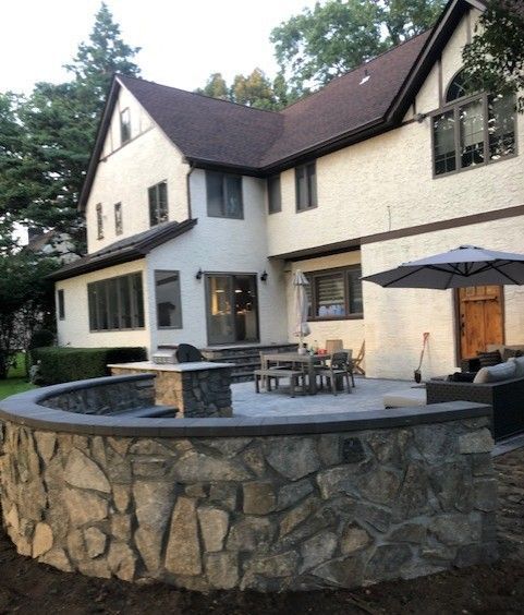 A large white house with a stone wall in front of it
