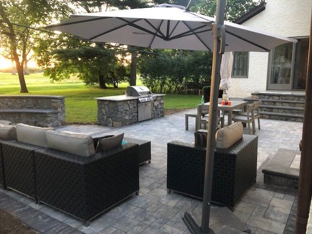 A patio with a couch and chairs under an umbrella