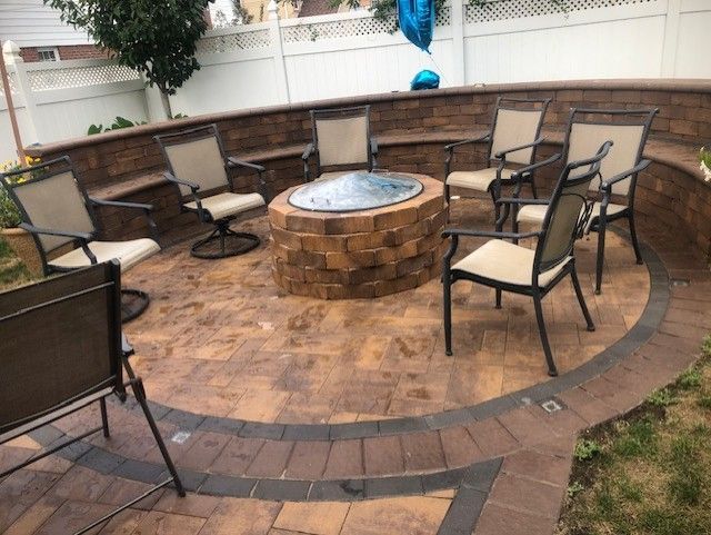 A fire pit is surrounded by chairs on a patio.