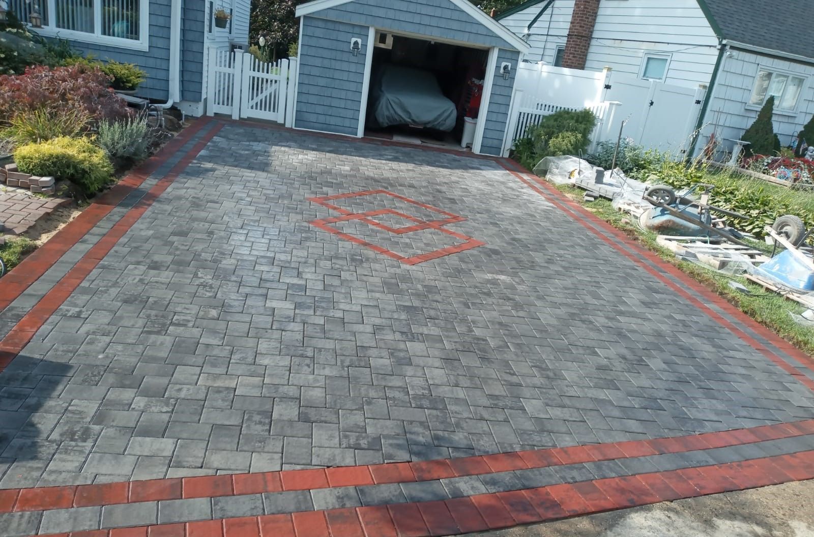 A car is parked in a garage next to a brick driveway.