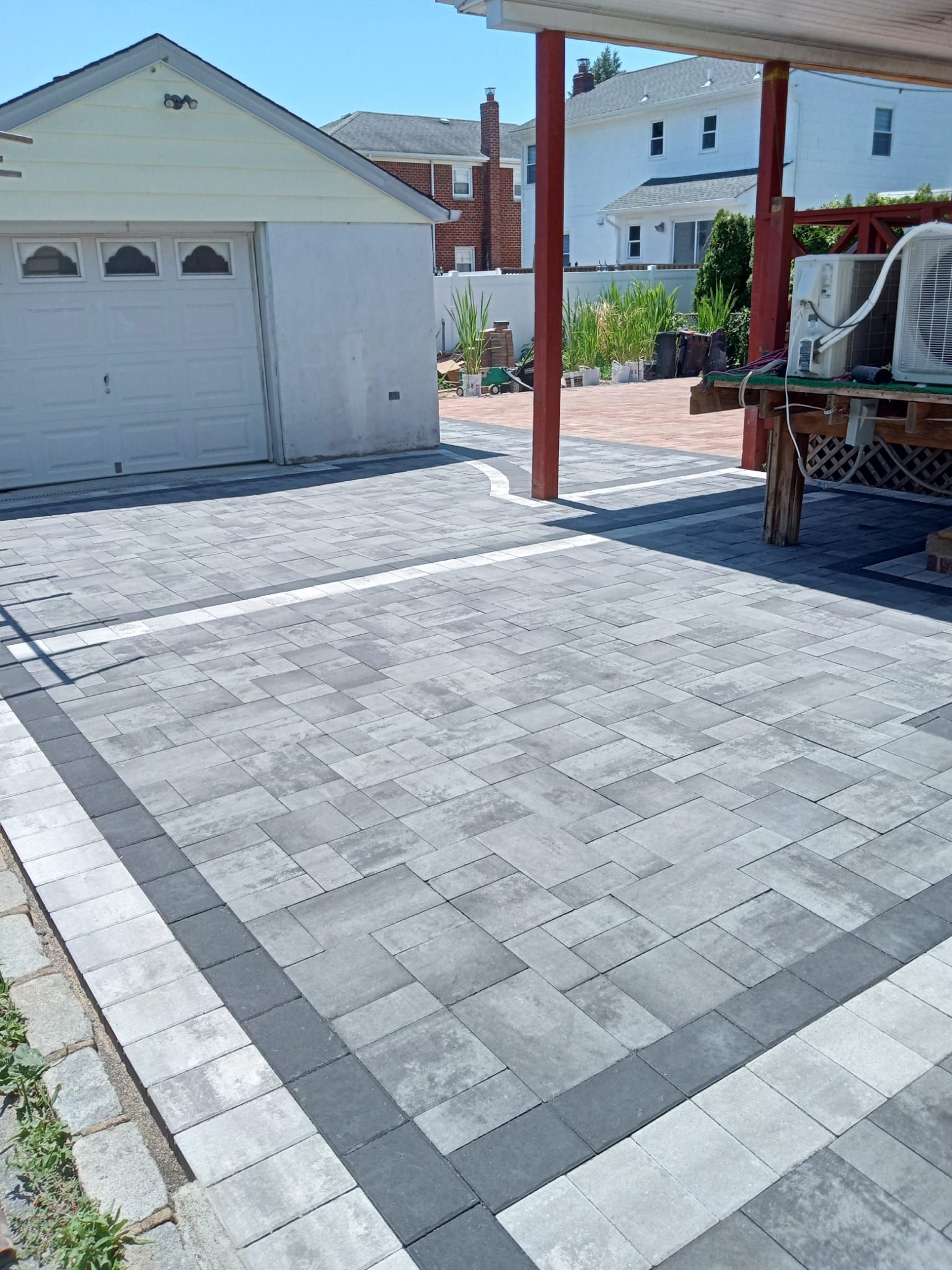 A brick driveway with a white garage in the background