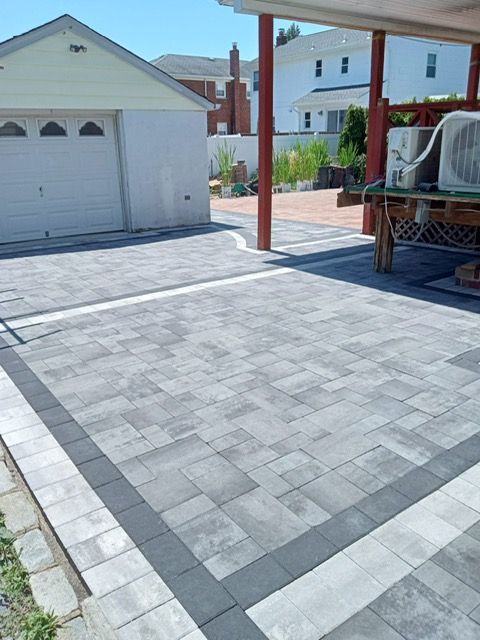 A brick driveway with a white garage in the background
