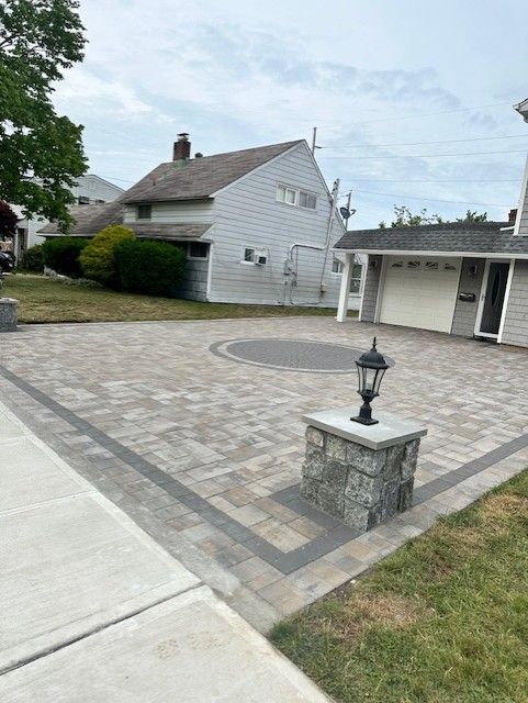 A driveway with a lamp post in front of a house.