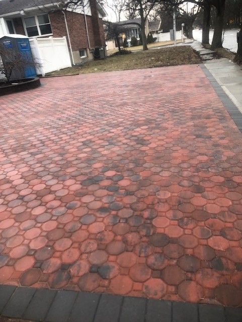A red brick driveway with circles on it is in front of a house.