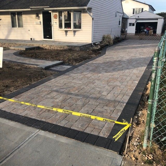A brick driveway with a yellow tape that says caution