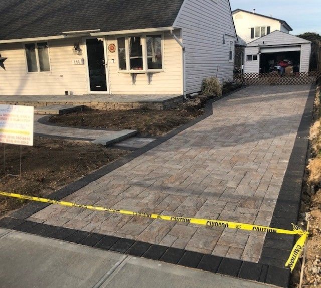 A brick driveway is being built in front of a house