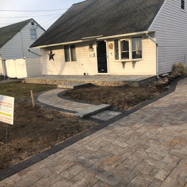 A white house with a brick walkway leading to it.