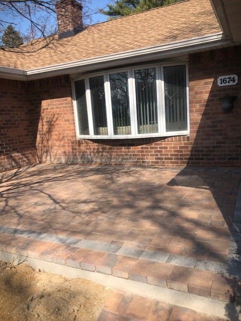 A brick house with a large window and a patio in front of it.