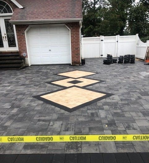 A brick driveway with a yellow caution tape around it in front of a house.