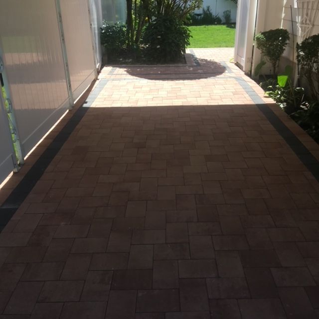 A brick walkway leading to a lush green yard