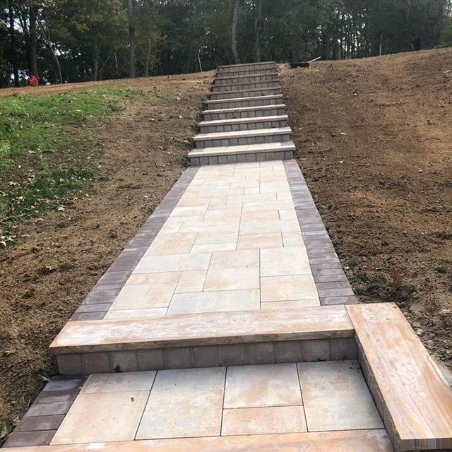 A brick walkway with stairs going up a hill