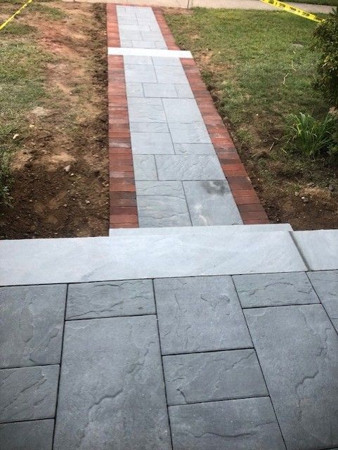 A brick walkway is being built in a yard.