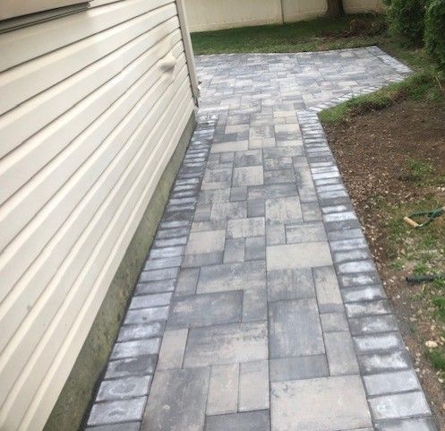 A brick walkway leading to the side of a house.