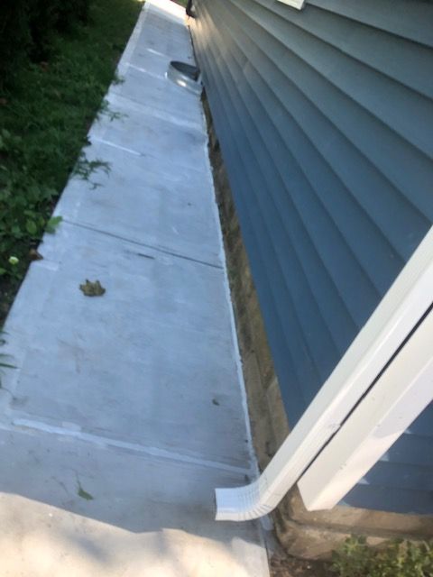 A sidewalk next to a house with a white railing