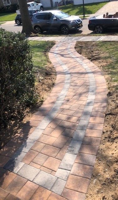 A brick walkway with a car parked on the side of it.
