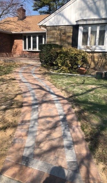 There is a brick walkway leading to a house.