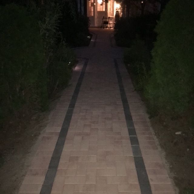 A brick walkway leading to a house at night