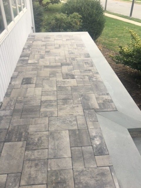 A brick walkway leading to a white house
