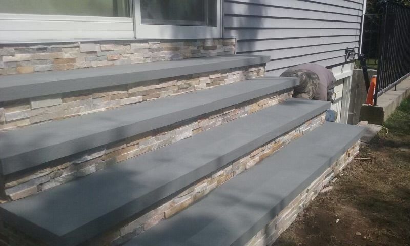 A set of stairs leading up to a house with a stone wall.