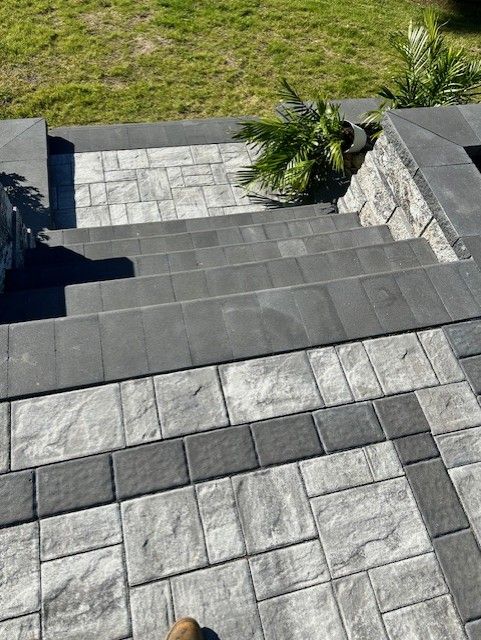 A person is standing on a patio with stairs made of bricks.