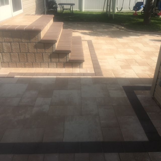 A patio with stairs and a swing set in the background.