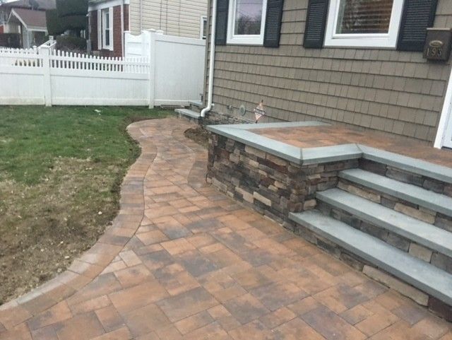 A brick walkway with stairs leading up to a house.